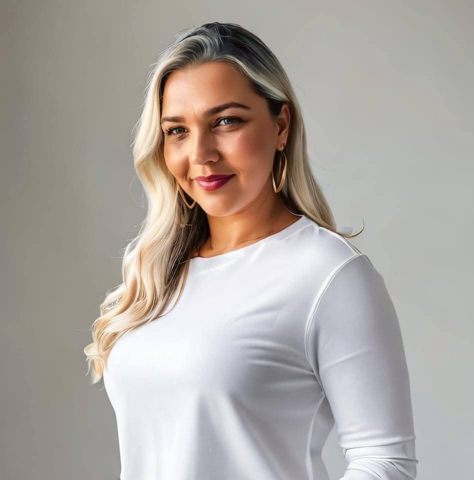 mulher sorrindo com cabelo loiro ondulado, usando blusa branca de manga longa e brincos argola dourados